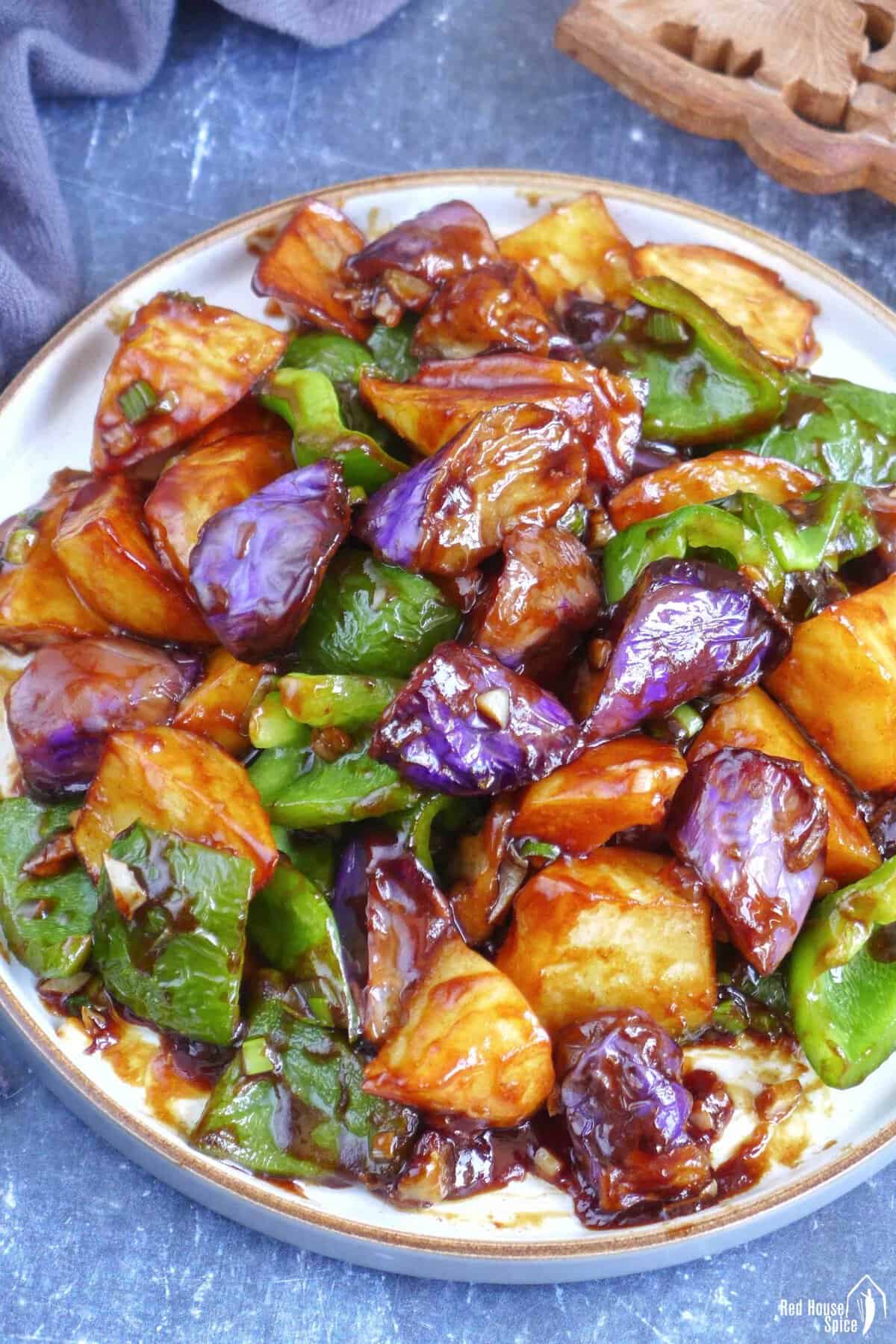 A plate of stir-fried eggplant, potato and pepper.