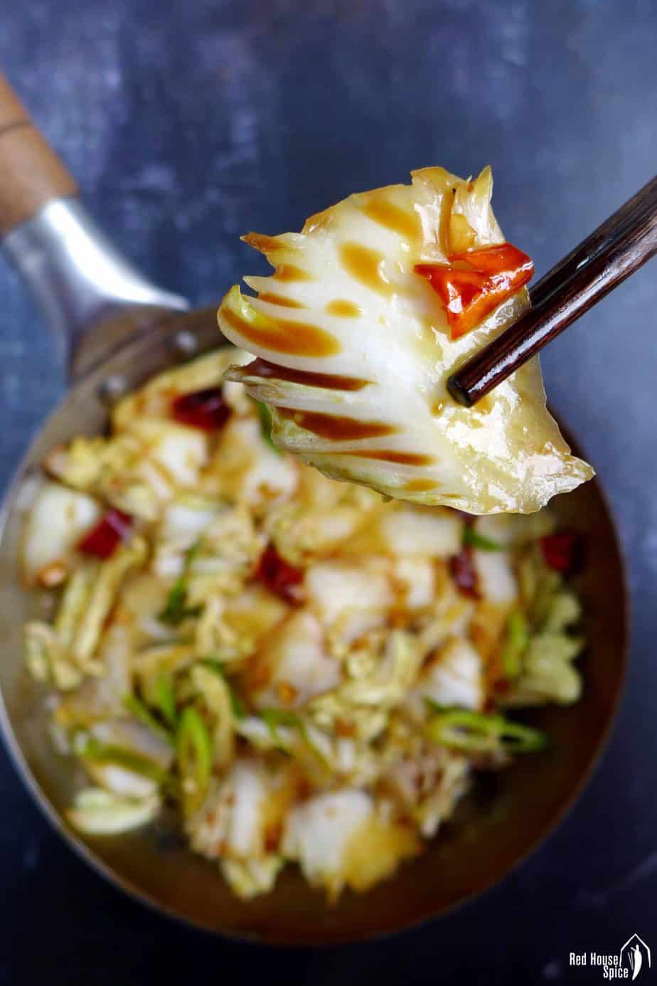 A piece of napa cabbage held by chopsticks