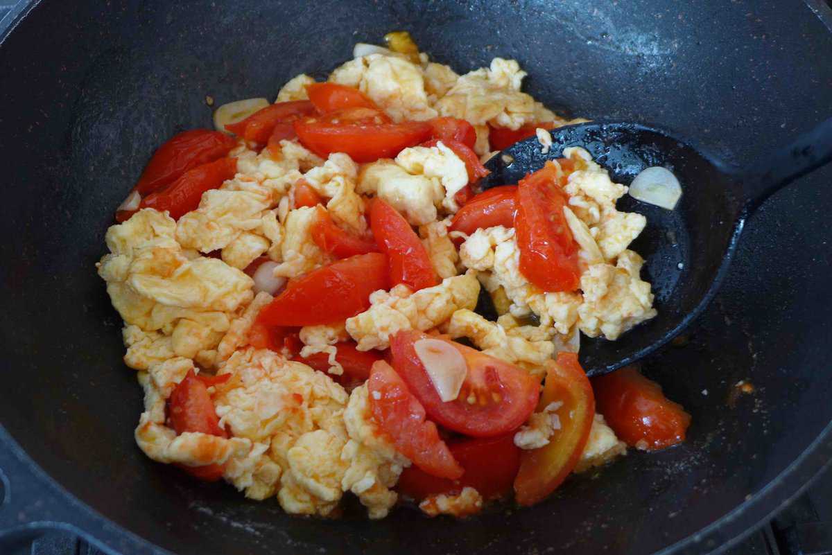 frying tomato and egg in a wok.