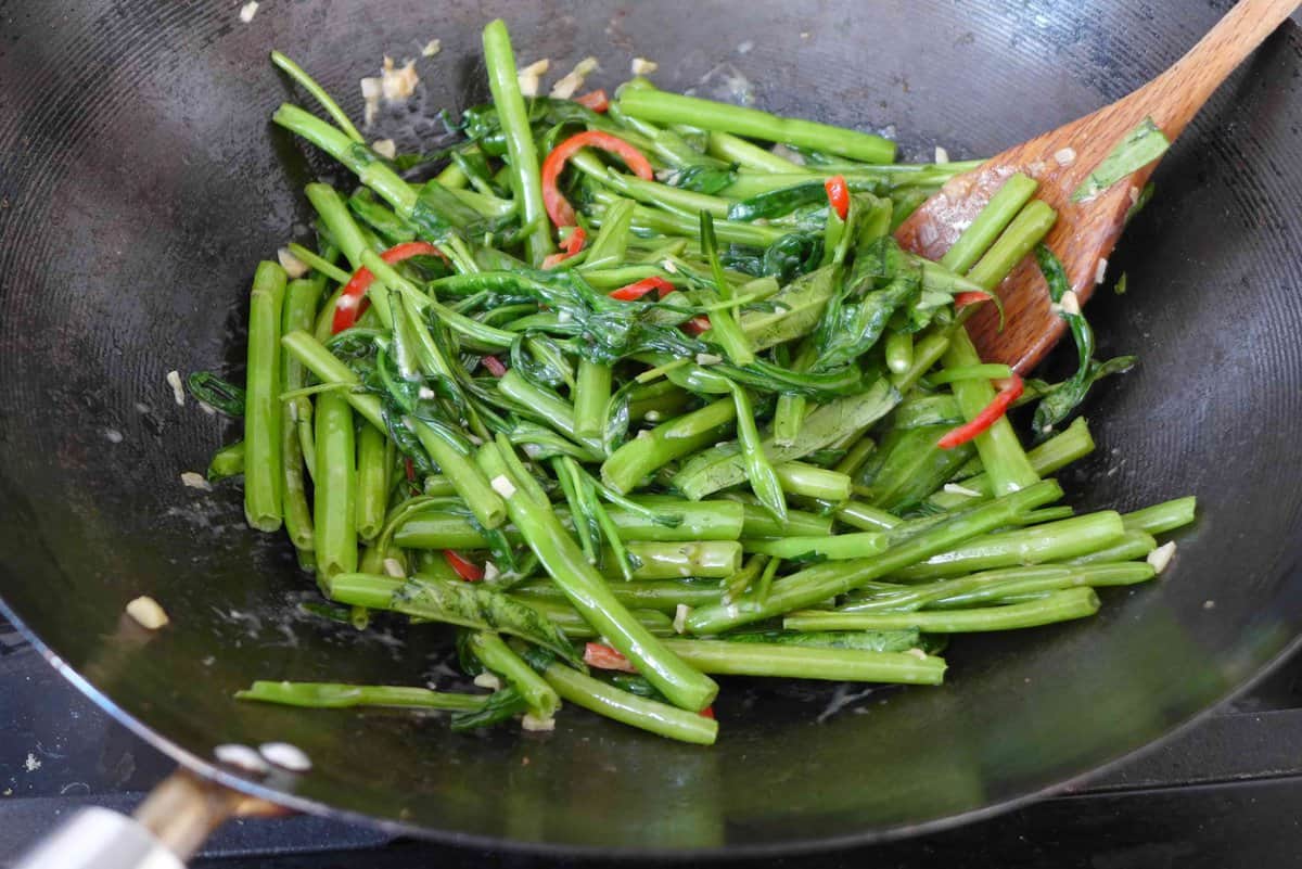 stir-frying water spinach in a wok