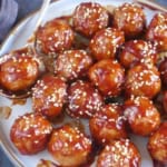 meatballs coated with sauce and sesame seeds with overlay text that says sweet and sour meatballs.