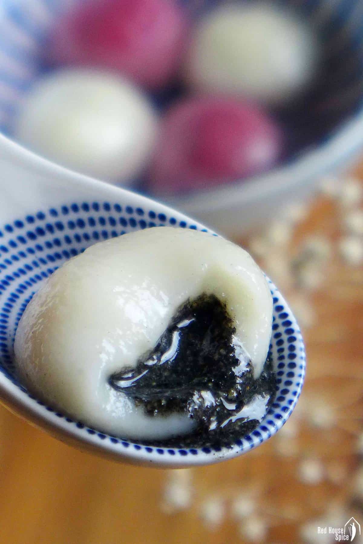 A half eaten white tang yuan with black sesame filling.