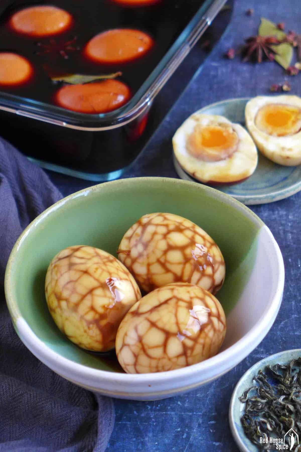 tea eggs in marinade, peeled tea eggs and halved tea eggs.
