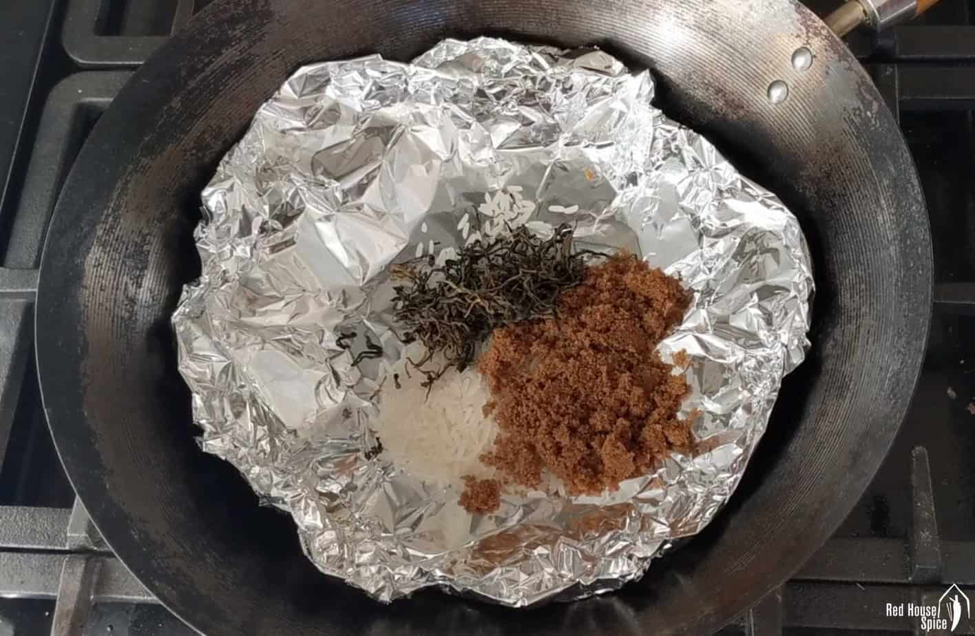 Tea leaves, sugar, rice on kitchen foil inside a wok