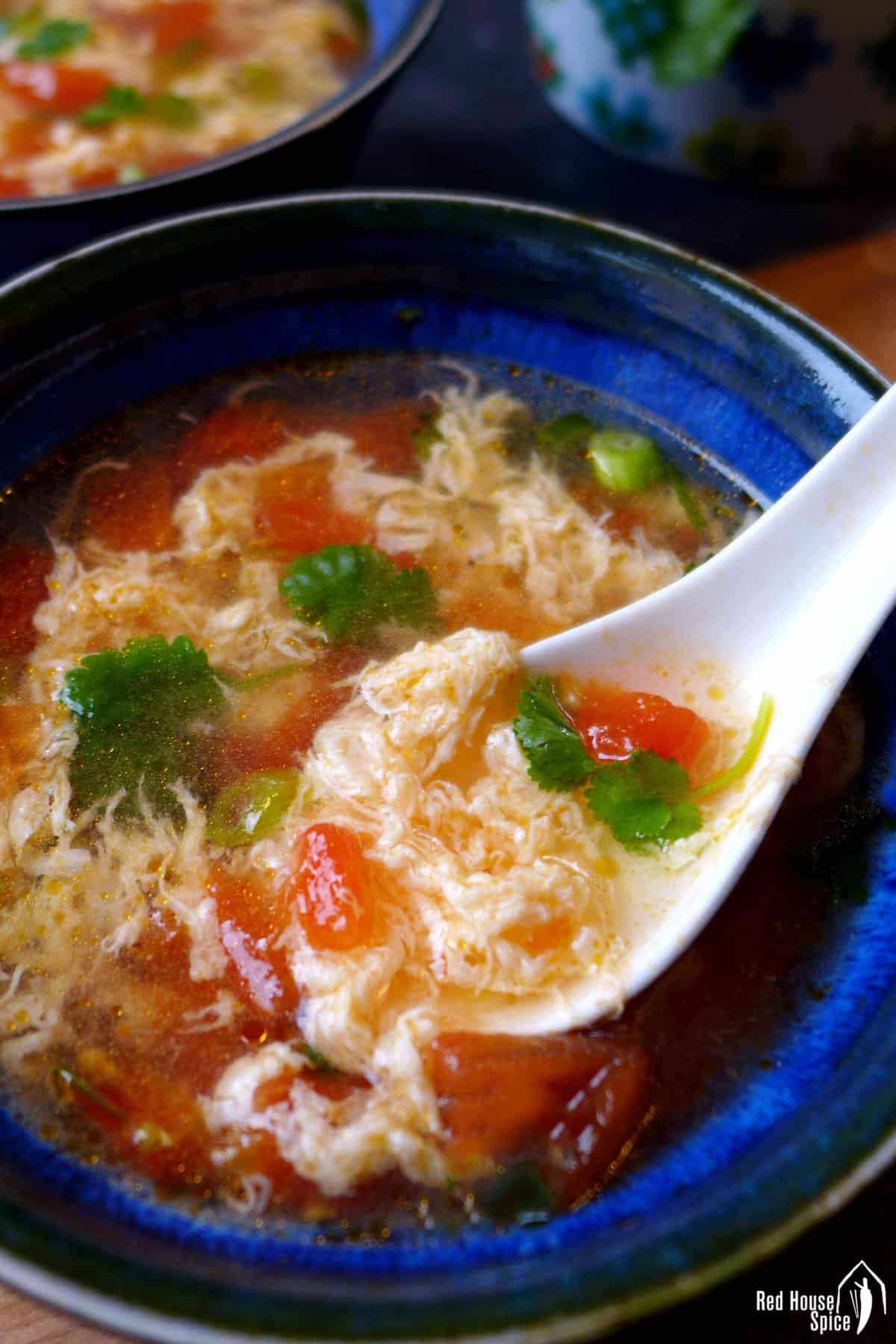 Spooning tomato egg drop soup.