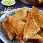 Fried shrimp toast on a plate with overlay text that says sesame shrimp toast.