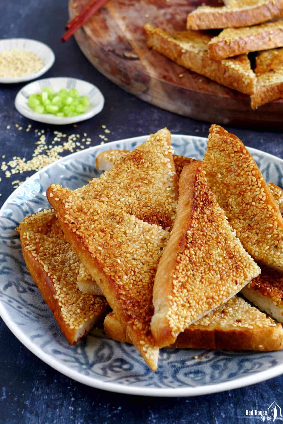 Trianglar shrimp toast on a plate and a chopping board.