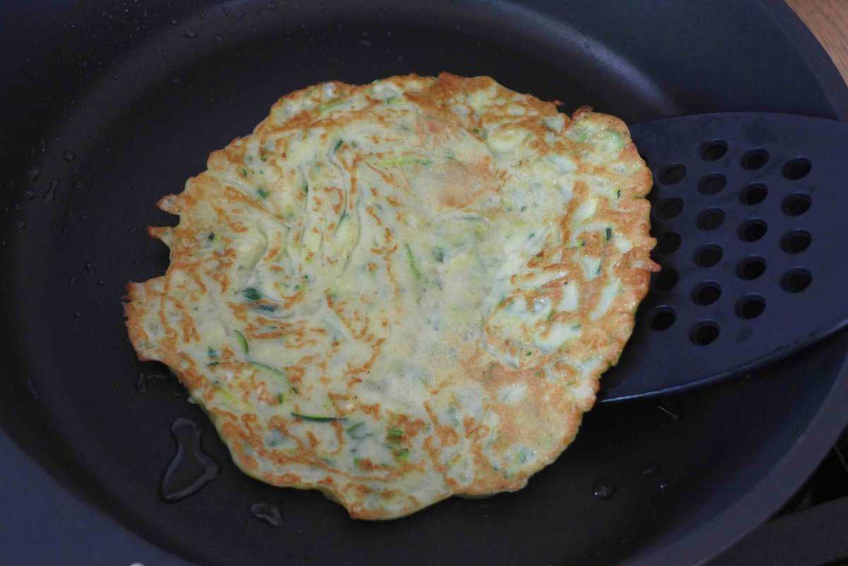 turning a zucchini pancake.