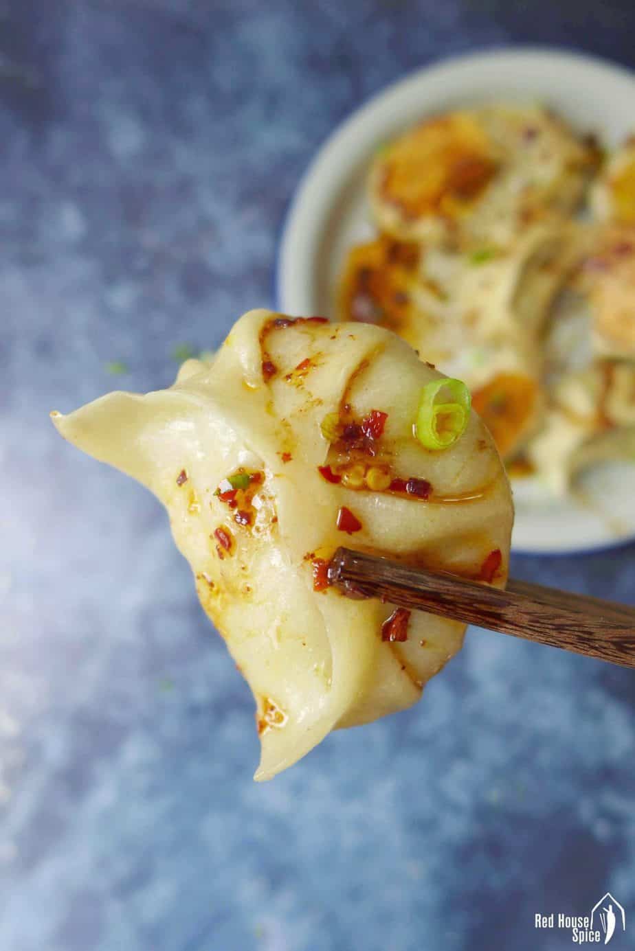 A vegan dumpling held by a pair of chopsticks