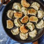 Pan fried vegan dumplings with dipping sauce on the side.