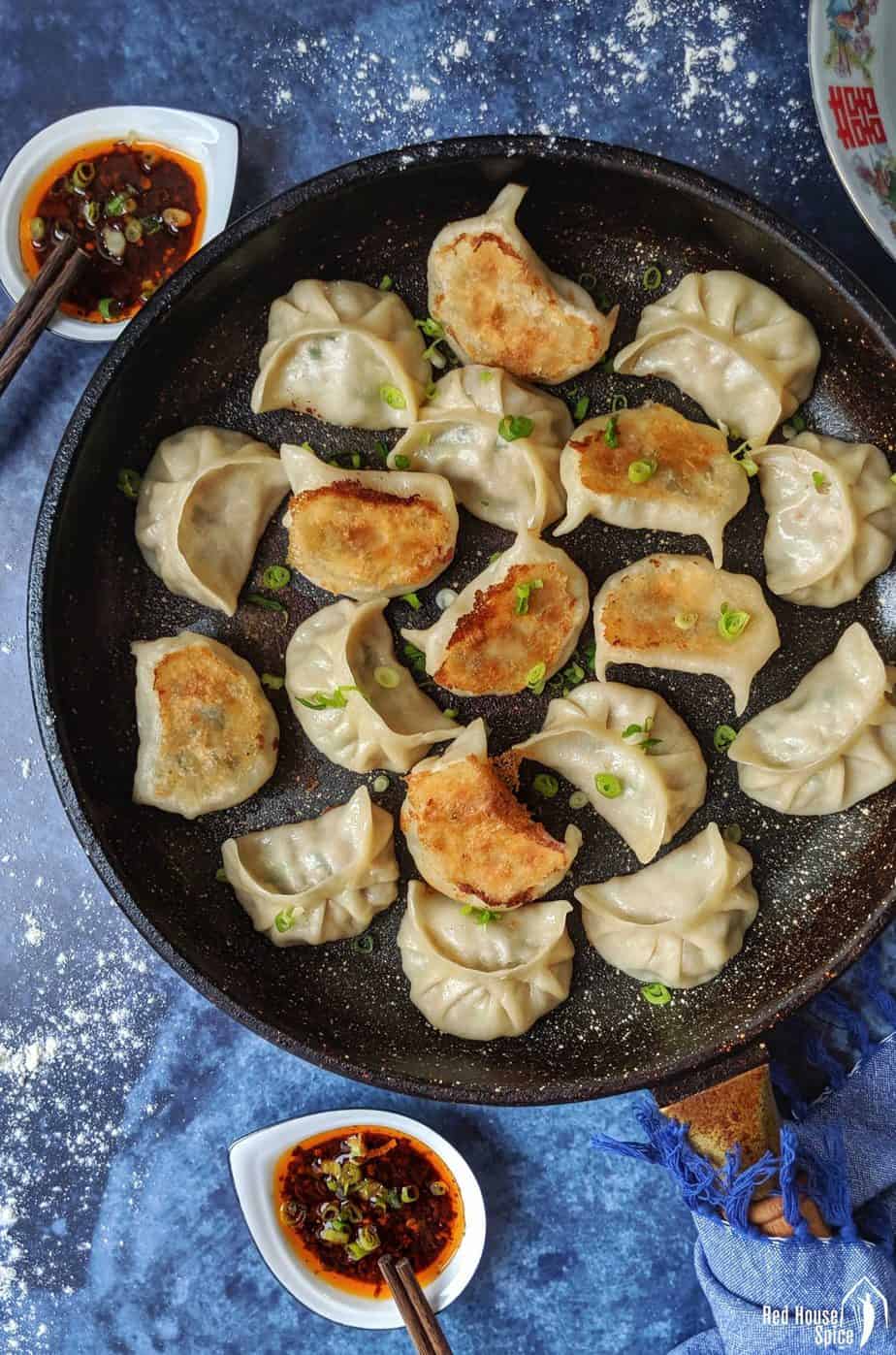 Pan fried dumplings with dipping sauce on the side.