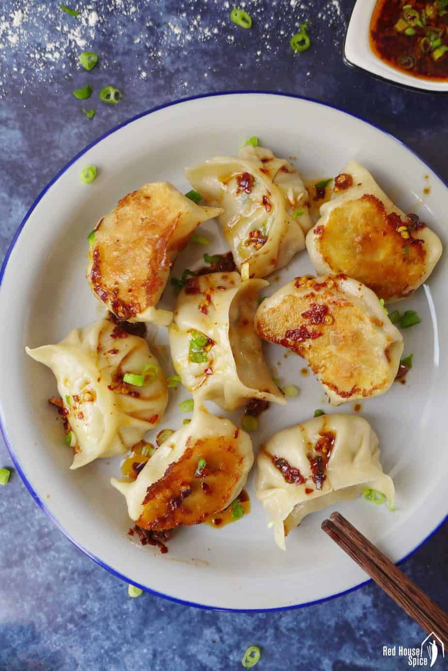 A plate of vegan dumplings covered with spicy sauce