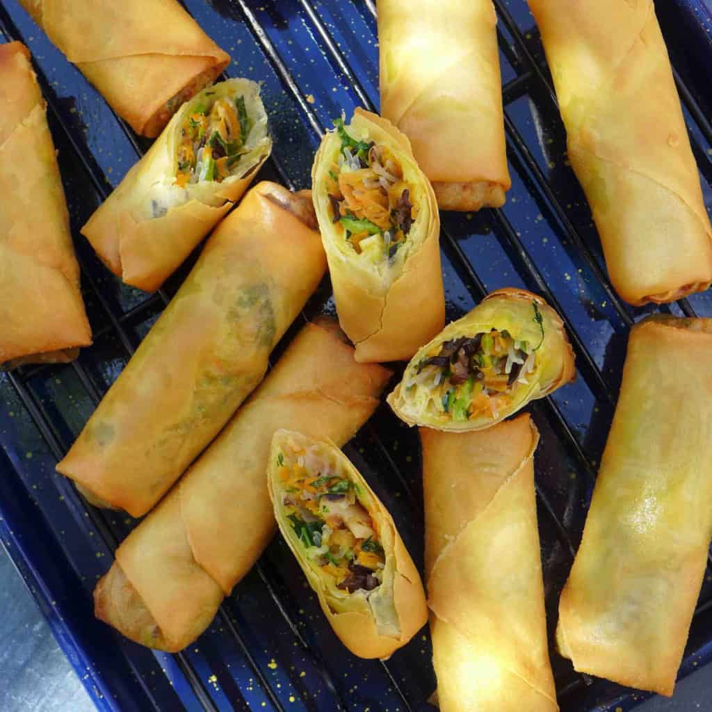 whole and halved veggie and tofu spring rolls on a tray.