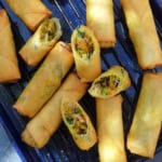 whole and halved veggie and tofu spring rolls on a tray.