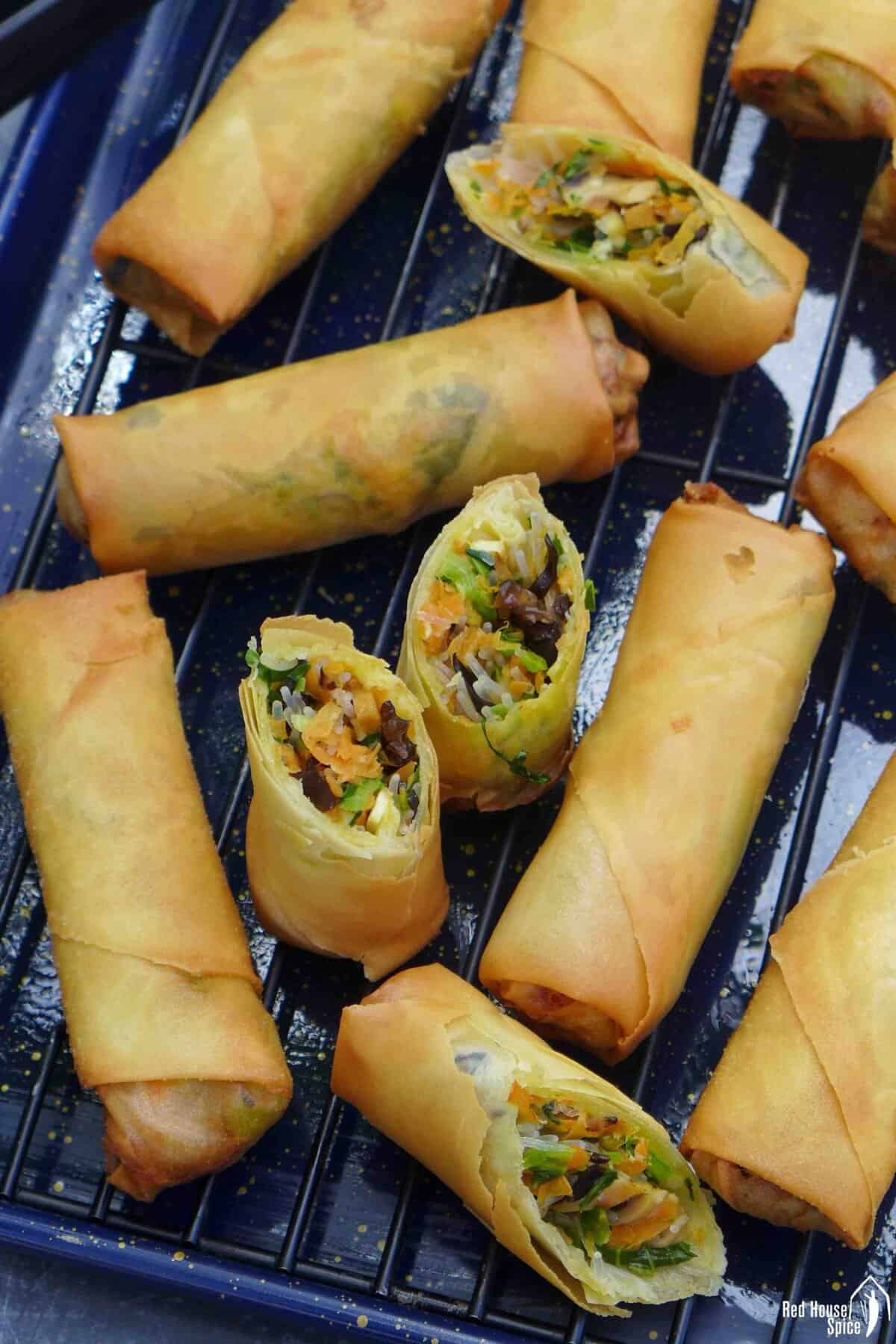 whole and halved veggie and tofu spring rolls on a tray.