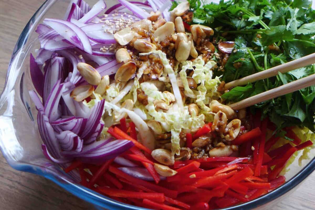 vegetables, nuts and dressing in a bowl.