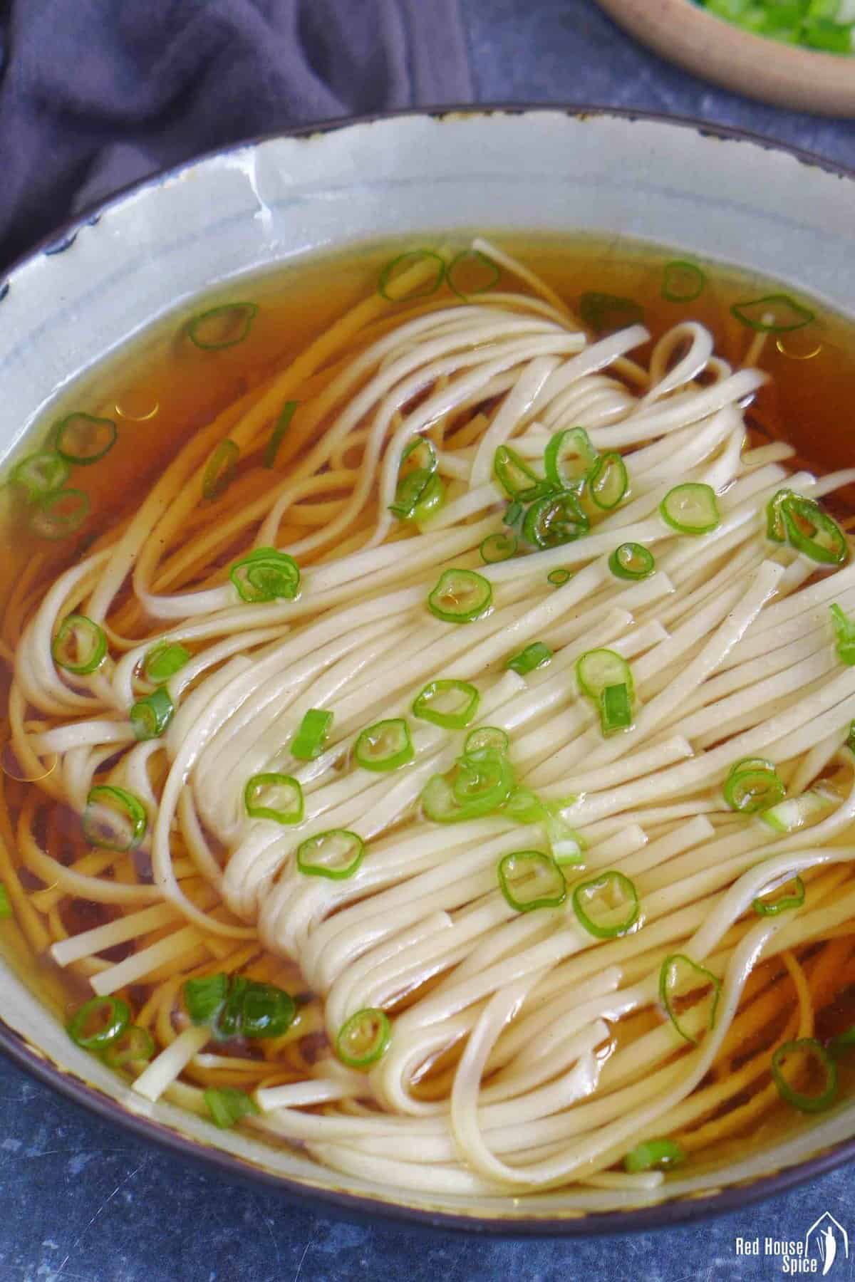 A bowl of Yang Chun Mian, noodle soup with clear broth and scallion garnish.