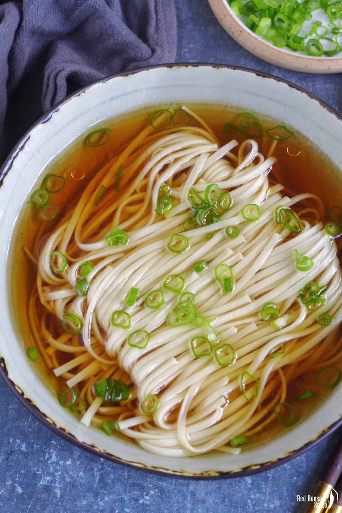 A bowl of Yang Chun Mian, noodle soup with clear broth and scallion garnish.
