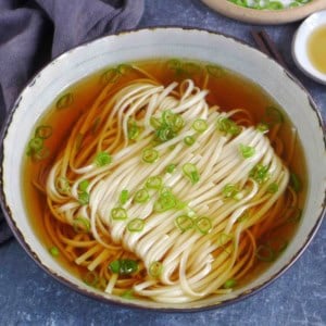 A bowl of Yang Chun Mian, noodle soup with clear broth and scallion garnish.