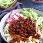 a bowl of Zha Jiang Mian, noodles with brown pork sauce and vegetable toppings.